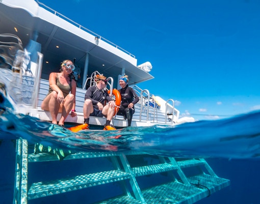 Tourists preparing to snorkel from a boat in the Great Barrier Reef's clear waters.