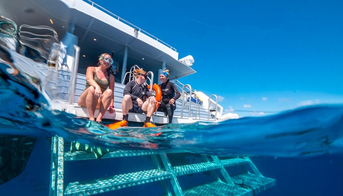 Tourists snorkelling in clear blue waters of Great Barrier Reef during full day cruise from Cairns.