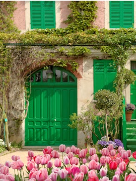 Tulips in front of Monet's house with green shutters in Giverny, France.