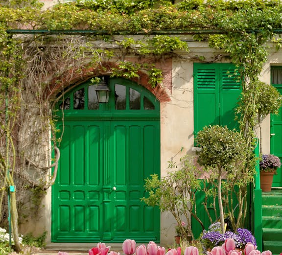Tulips in front of Monet's house with green shutters in Giverny, France.