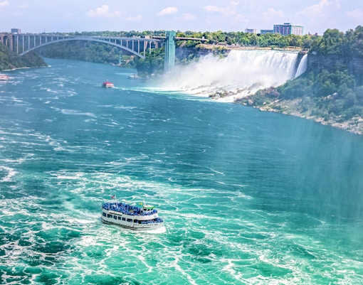 Maid of Mist boat approaching Niagara Falls, USA, with mist rising from cascading water.