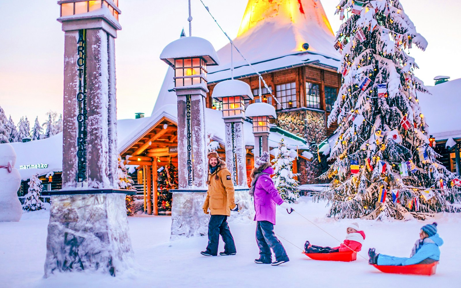 Guided tour at Santa Claus Village Rovaniemi with children sledding in snow.