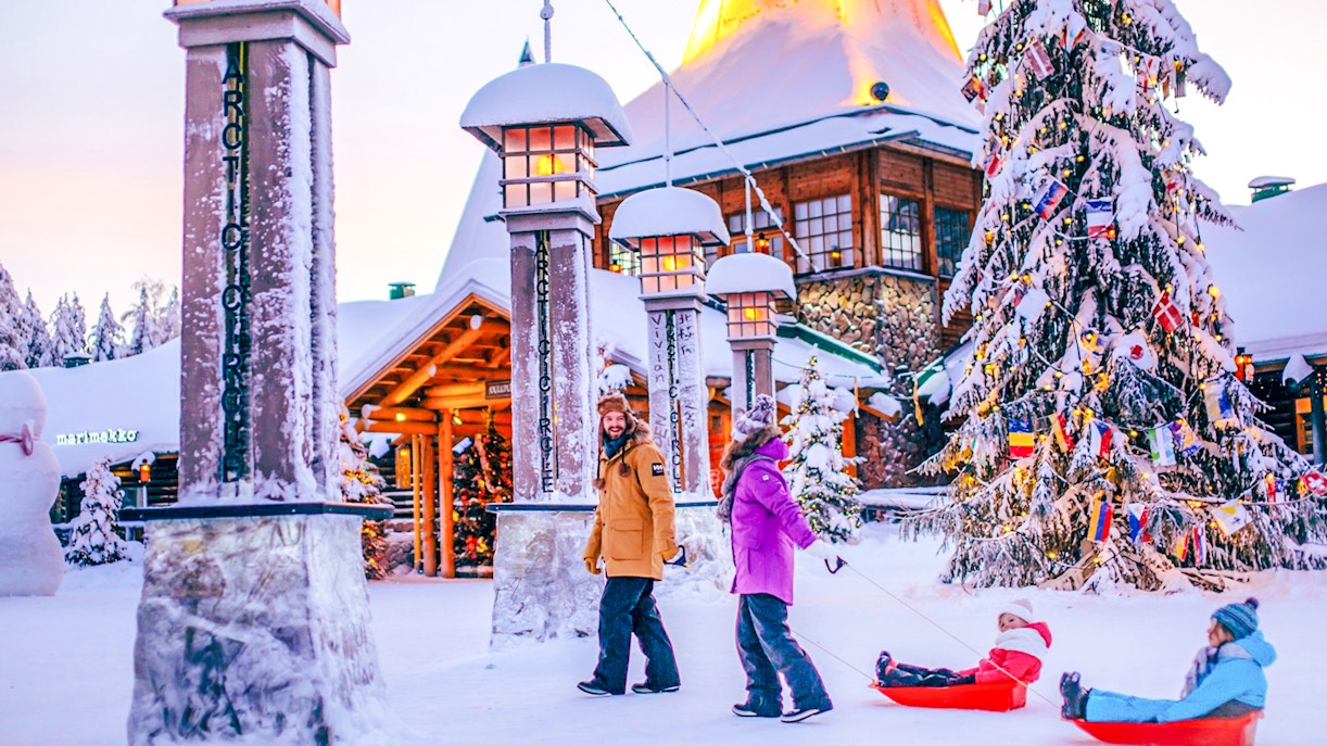 Guided tour at Santa Claus Village Rovaniemi with children sledding in snow.
