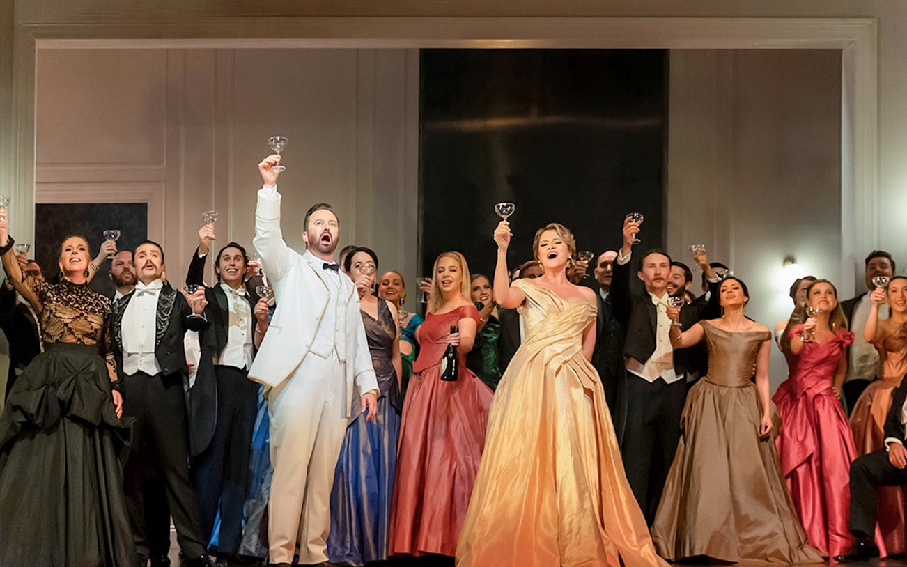 Performers in formal attire raising glasses during La Traviata at Sydney Opera House.