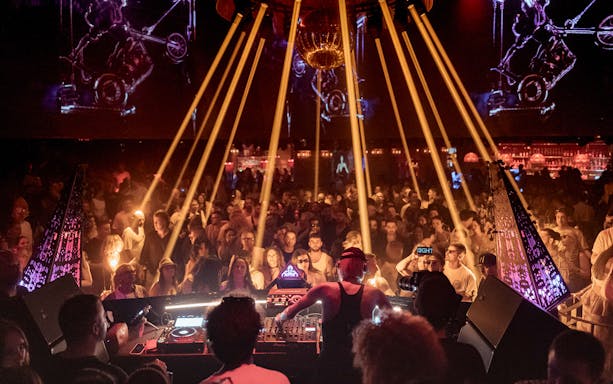 DJ performing at Club Chinois with vibrant crowd and dynamic lighting.