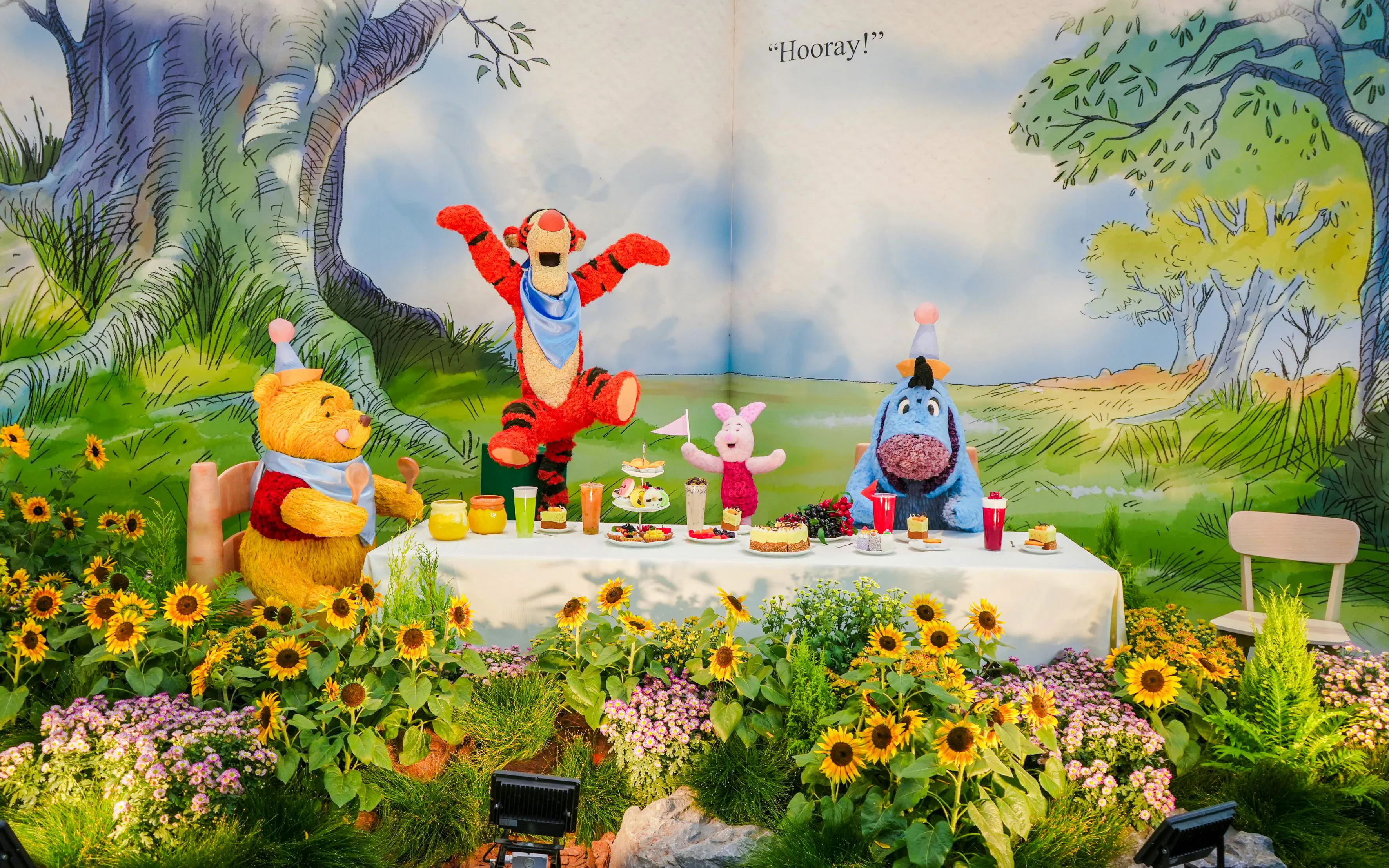 Characters enjoying a picnic in Disney Garden of Wonder with sunflowers and treats.