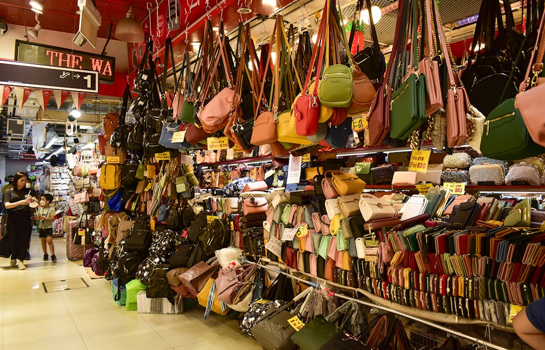 Bugis Street Market in Singapore with colorful handbags and wallets on display.