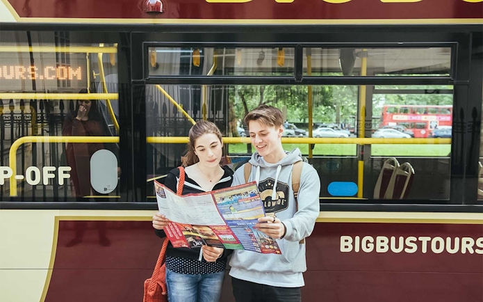 Tourists reading a map in front of a Big Bus Tours bus in London.