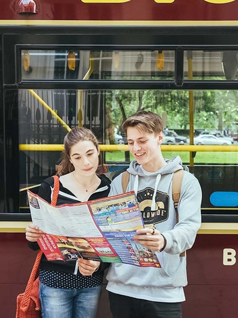 Tourists reading a map in front of a Big Bus Tours bus in London.