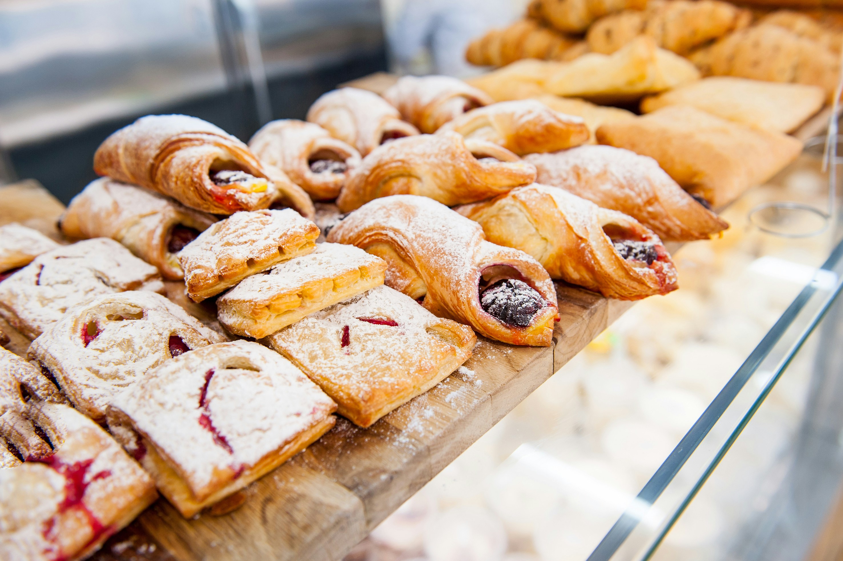 Assorted pastries with fruit filling and powdered sugar on display.