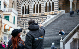 Tour guide pointing at Amalfi Cathedral steps in Amalfi, Italy.