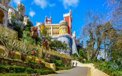 Pena Palace in Sintra with colorful towers and a winding path lined with greenery.
