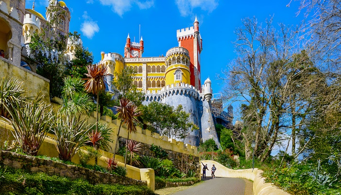 Pena Palace in Sintra with colorful towers and a winding path lined with greenery.