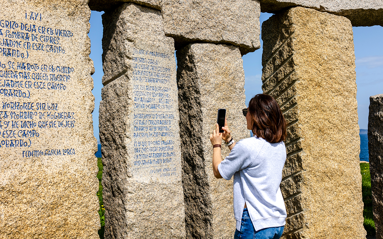 Person photographing stone monument with inscriptions at Stonehenge.
