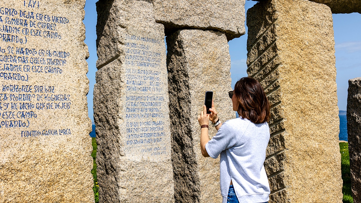 Person photographing stone monument with inscriptions at Stonehenge.