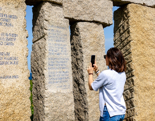 Person photographing stone monument with inscriptions at Stonehenge.