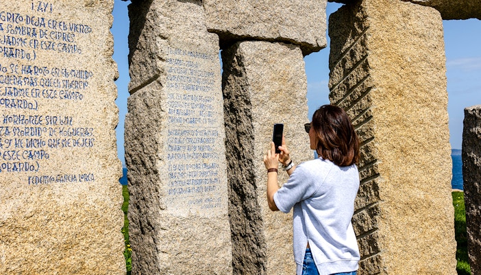 Person photographing stone monument with inscriptions at Stonehenge.