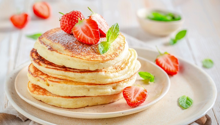 Stack of pancakes with syrup and butter on top.