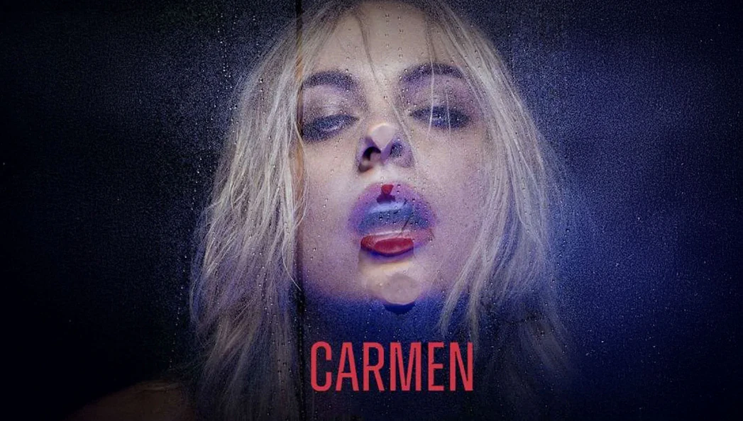 Blonde woman with wet hair and red lips behind a glass pane, text "Carmen" below.