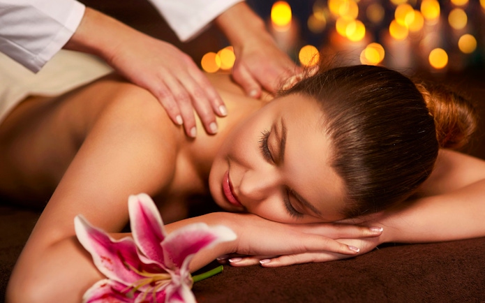 Woman receiving a back massage at Mandala Day Spa with a pink lily nearby.