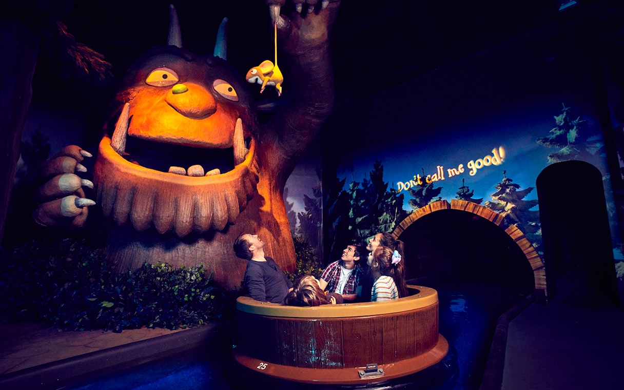 Visitors on a boat ride encounter a large Gruffalo figure at the Gruffalo River Ride Adventure.
