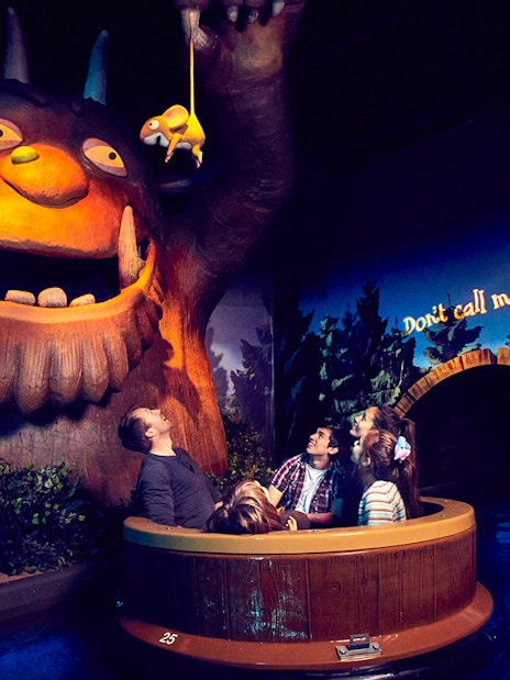 Visitors on a boat ride encounter a large Gruffalo figure at the Gruffalo River Ride Adventure.