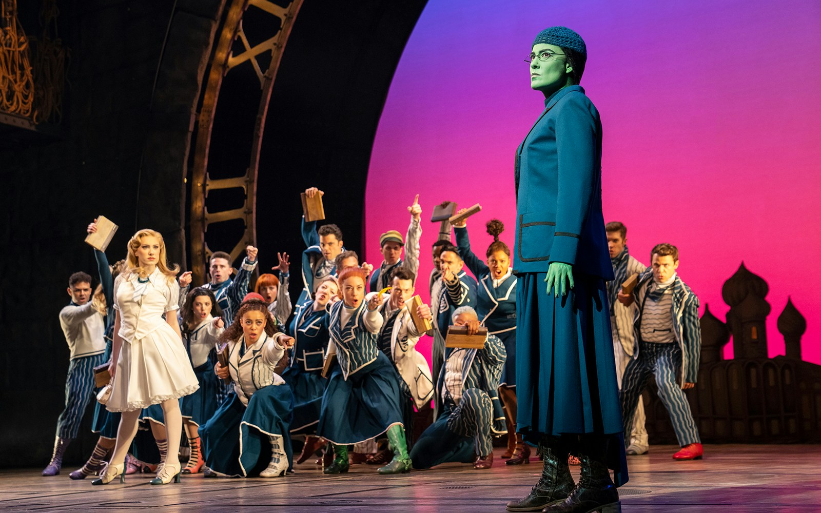 Stage scene from the musical Wicked with characters in costume during a dramatic moment.