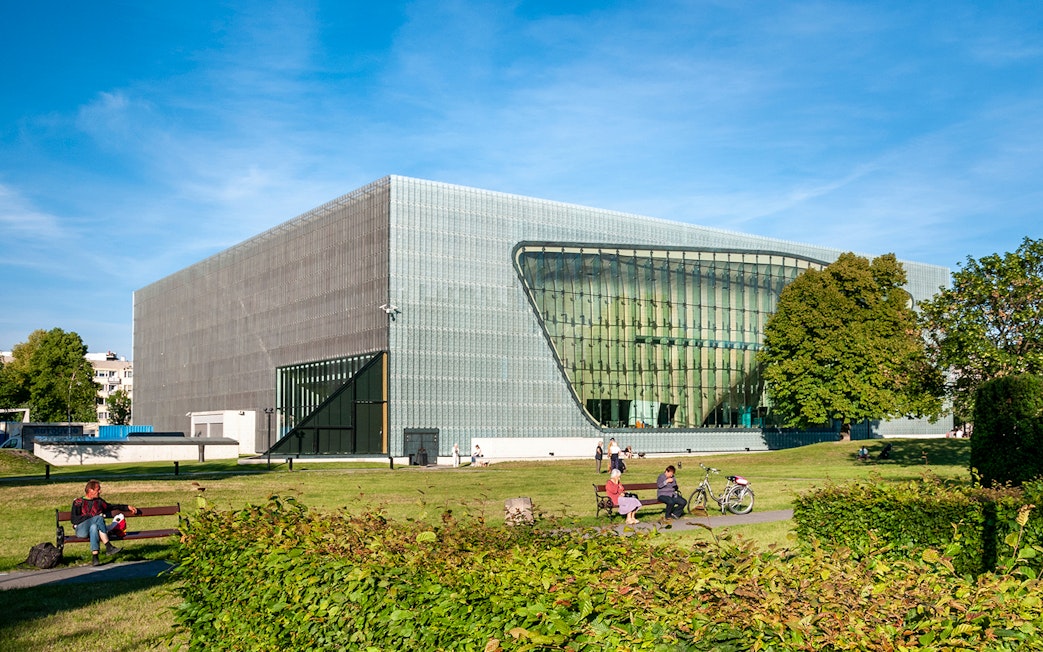 Polin Museum exterior with visitors on benches in Warsaw, Poland.