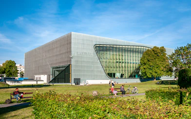 Polin Museum exterior with visitors on benches in Warsaw, Poland.