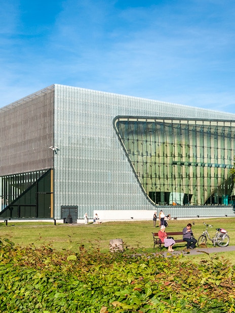 Polin Museum exterior with visitors on benches in Warsaw, Poland.