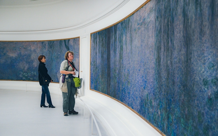 Tourist viewing Monet's Water Lilies at Orangerie Museum, Paris.