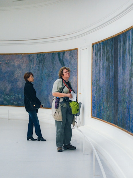 Tourist viewing Monet's Water Lilies at Orangerie Museum, Paris.