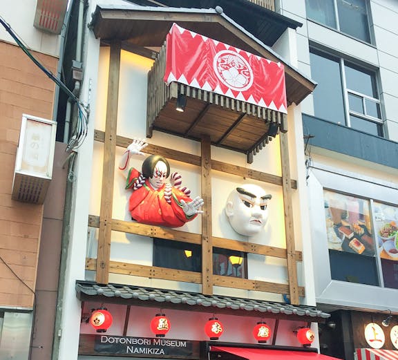 Dotonbori Museum Namikiza entrance with traditional Japanese masks and red lanterns.