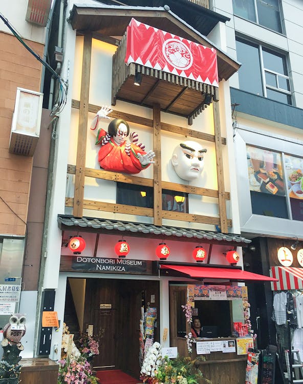 Dotonbori Museum Namikiza entrance with traditional Japanese masks and red lanterns.