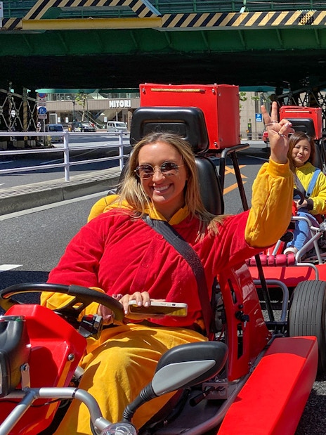 Participants driving go-karts in colorful outfits on a street in Shibuya, Tokyo.