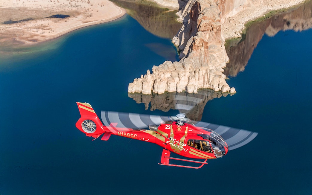 Helicopter flying over Horseshoe Bend with river and rock formations below.