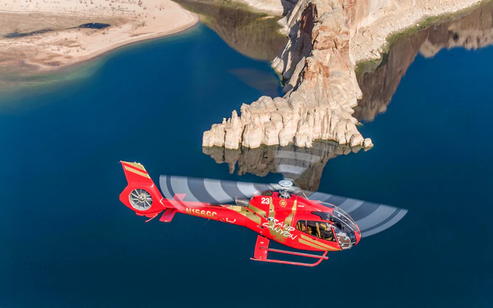 Helicopter flying over Horseshoe Bend with river and rock formations below.