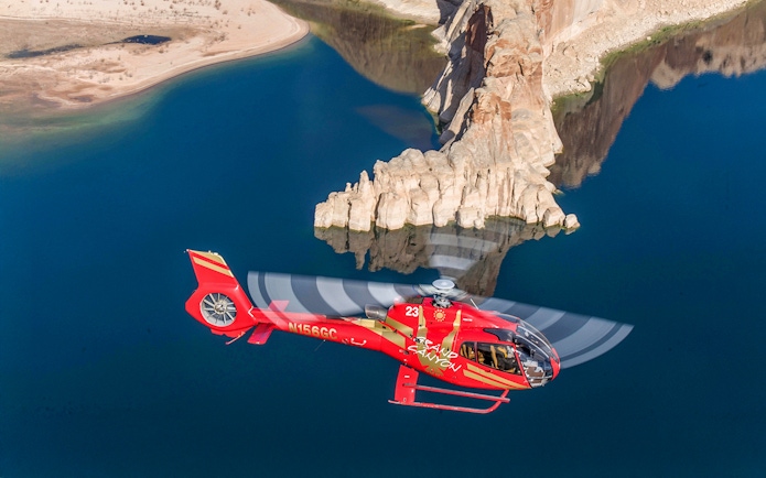 Helicopter flying over Horseshoe Bend with river and rock formations below.