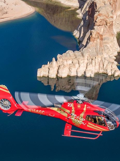 Helicopter flying over Horseshoe Bend with river and rock formations below.