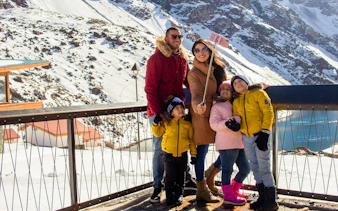 Family taking a selfie at snowy Portillo resort with mountains in the background.