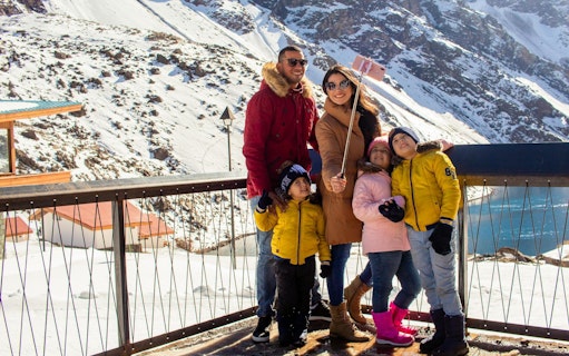Family taking a selfie at snowy Portillo resort with mountains in the background.