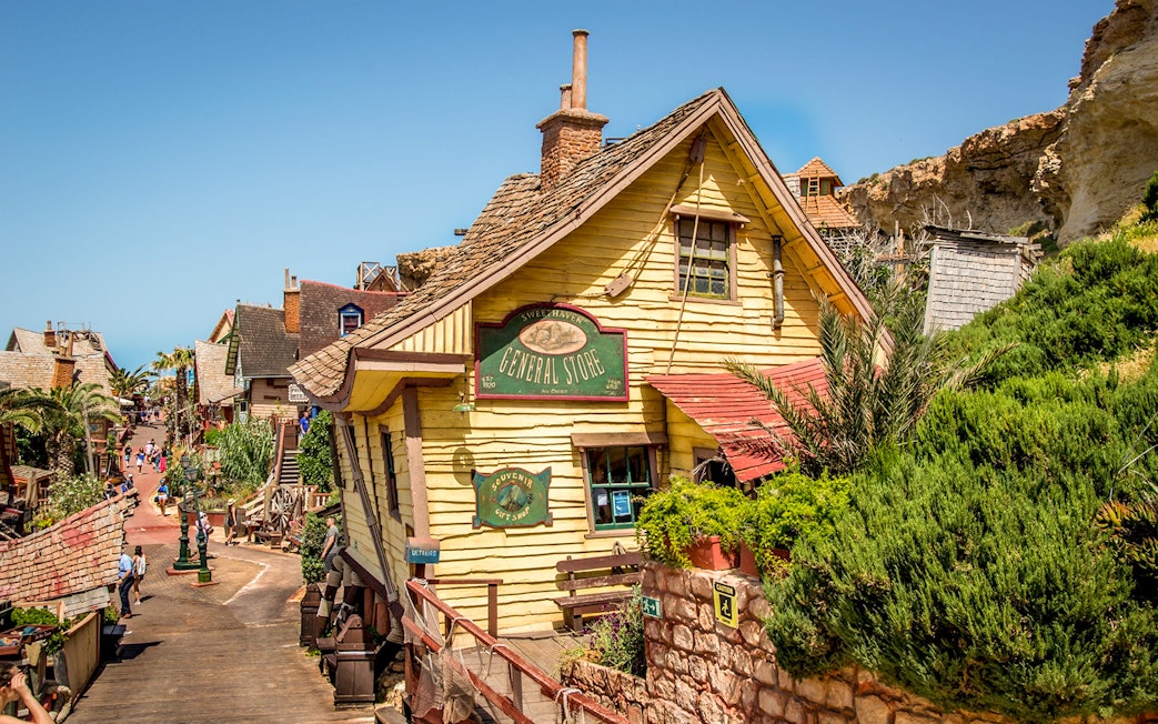 General store facade in Popeye Village, Malta, with colorful wooden buildings and greenery.