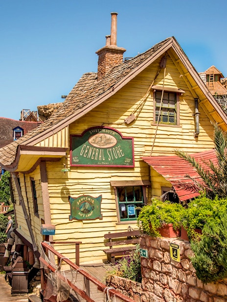 General store facade in Popeye Village, Malta, with colorful wooden buildings and greenery.