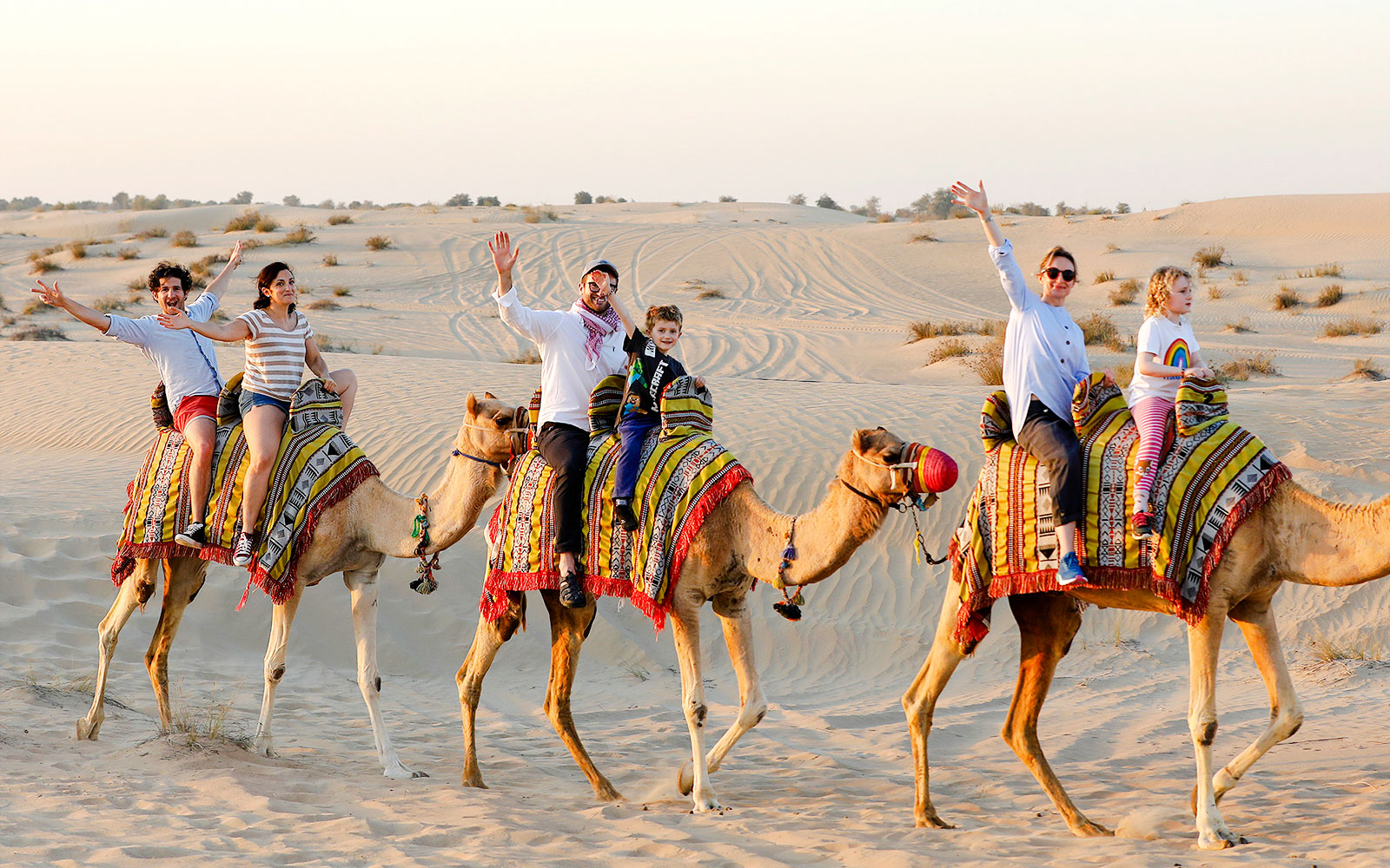 Camel ride in Abu Dhabi desert with tourists enjoying the safari experience.