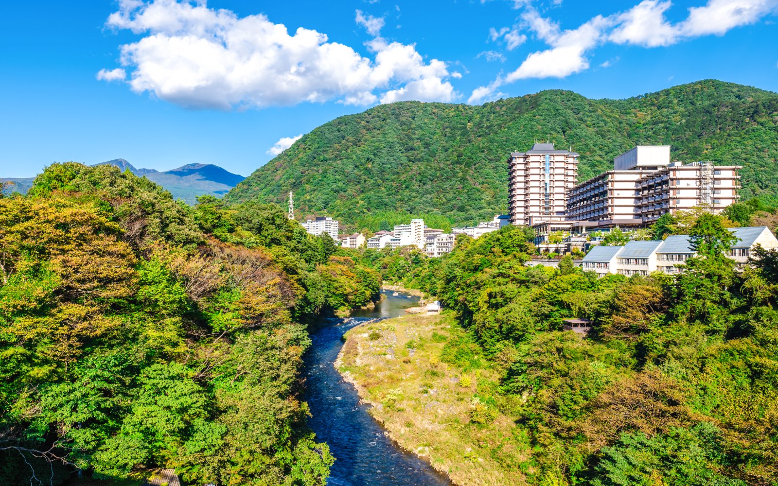 Kinu River flowing through Kinugawa Onsen with lush greenery and spa town buildings in Nikko.