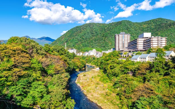 Kinu River flowing through Kinugawa Onsen with lush greenery and spa town buildings in Nikko.