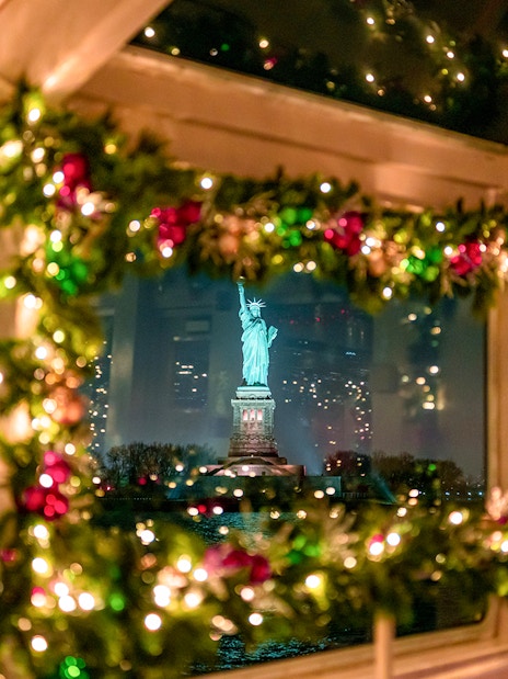 Statue of Liberty viewed through decorated cruise window at night.