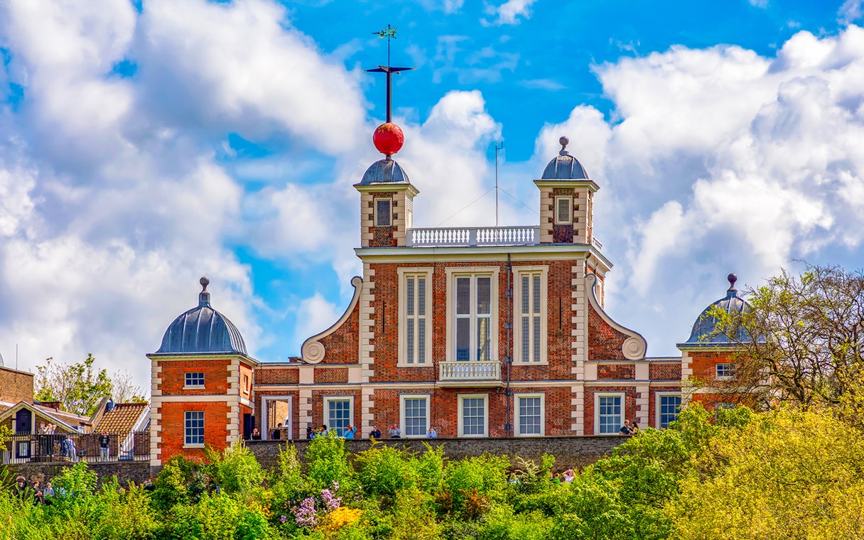 Royal Observatory Greenwich with iconic red time ball against a cloudy sky.