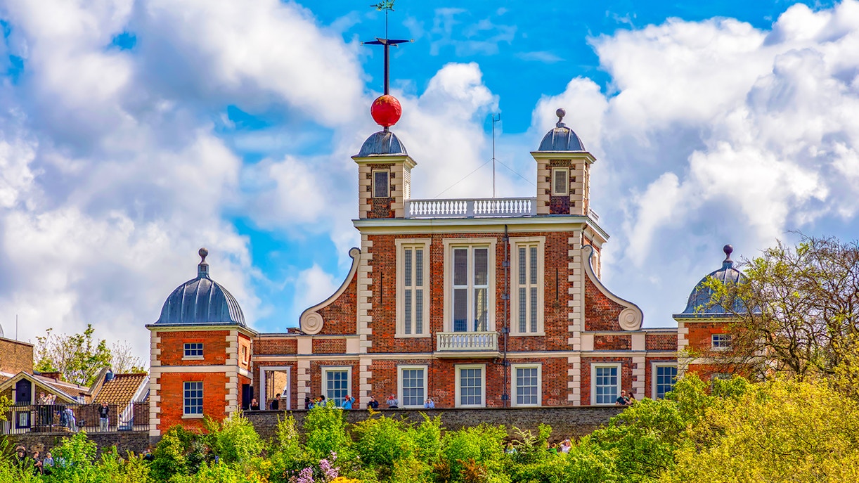 Royal Observatory Greenwich with iconic red time ball against a cloudy sky.