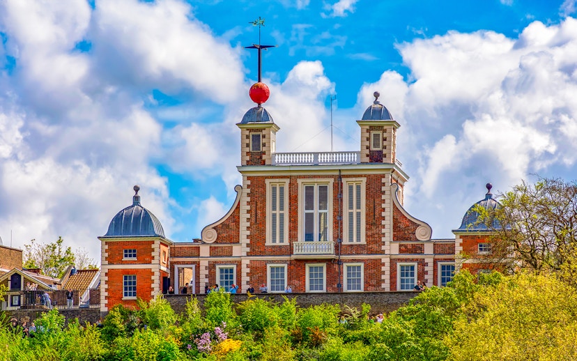 Royal Observatory Greenwich with iconic red time ball against a cloudy sky.